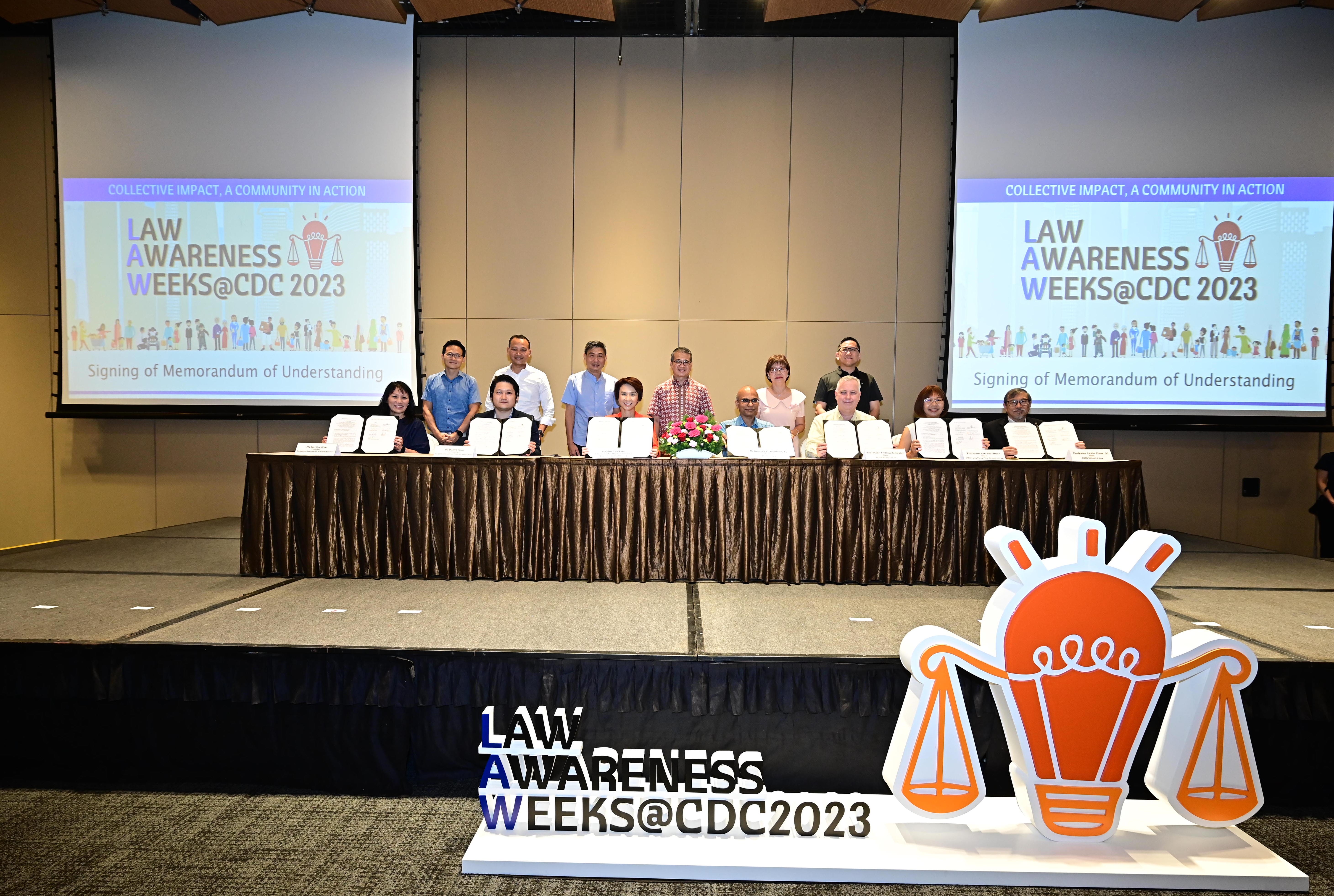 A group of people are on stage with open documents in front of a screen displaying "Law Awareness Weeks@CDC 2023".